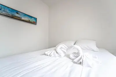 a white bed with white sheets and a painting on the wall at Zonnebloem in Zandvoort