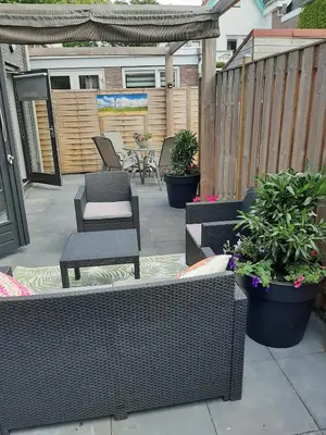 a patio with chairs and tables and potted plants at Zomerhuis Carolina in Egmond aan Zee