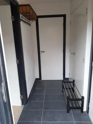 a hallway with two white doors and a bench at Zomerhuis Carolina in Egmond aan Zee