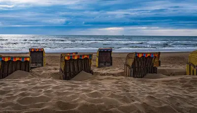 a group of beach chairs on the sand on the beach at La Playa in Egmond aan Zee