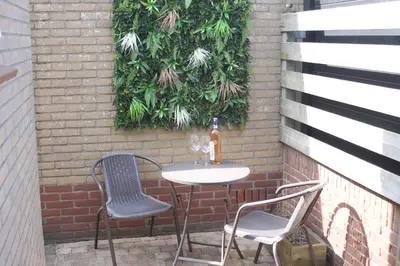 a table and two chairs and a bottle of wine at La Playa in Egmond aan Zee