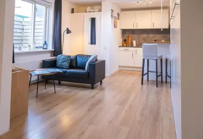 a living room with a couch and a kitchen at La Playa in Egmond aan Zee