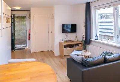 a living room with a couch and a television at La Playa in Egmond aan Zee