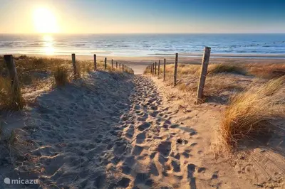 a sandy beach with a fence and the ocean at La Playa in Egmond aan Zee
