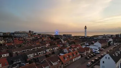 a view of a city with a lighthouse in the distance at La Playa in Egmond aan Zee