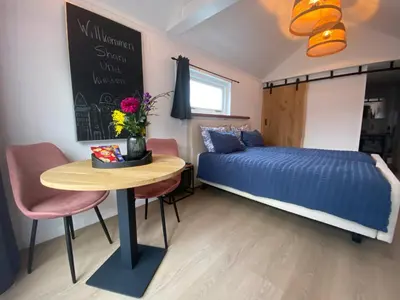 a small bedroom with a bed and a table with a blue bed at Style Gardenhouse Zwanenburg near AMSTERDAM, HAARLEM, ZANDVOORT in Zwanenburg
