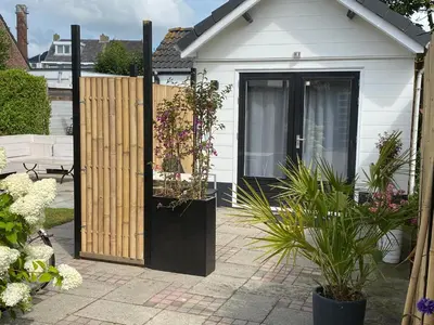 a white house with a wooden door with plants at Style Gardenhouse Zwanenburg near AMSTERDAM, HAARLEM, ZANDVOORT in Zwanenburg