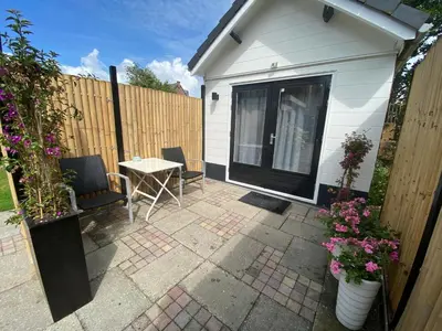 a patio with a table and chairs and a fence at Style Gardenhouse Zwanenburg near AMSTERDAM, HAARLEM, ZANDVOORT in Zwanenburg