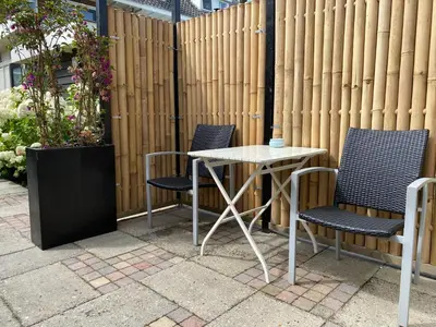 a table and chairs on a patio next to a fence at Style Gardenhouse Zwanenburg near AMSTERDAM, HAARLEM, ZANDVOORT in Zwanenburg