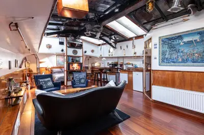 a living room with a chair and a kitchen at Anna Houseboat in Amsterdam
