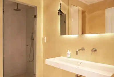a bathroom with a sink and a shower with a mirror at The Little Townhouse in Amsterdam