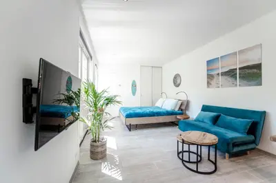 a living room with a blue couch and a tv at Good Vibes Romantic Studio incl free private parking in Zandvoort