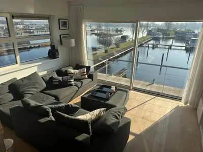 a living room with two couches and a large window at The Boathouse with boat in Aalsmeer