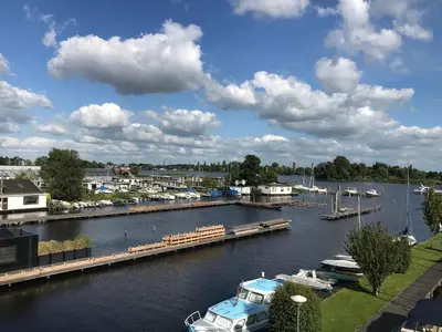 a boat docked at a dock in a river at The Boathouse with boat in Aalsmeer