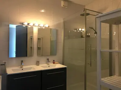 a bathroom with a sink and a shower with a mirror at The Boathouse with boat in Aalsmeer