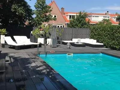 a swimming pool with white chairs and a table at Finch guesthouse in Zandvoort