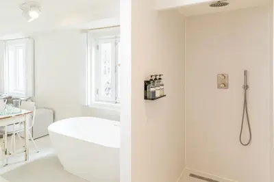 a white bathroom with a tub and a shower at Luttik in Alkmaar