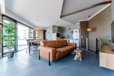 a living room with a brown couch and a kitchen at beach apartments in Zandvoort