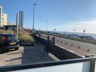 a car parked next to a road next to the ocean at beach apartments in Zandvoort
