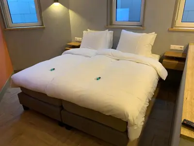a large bed with white sheets and pillows in a room at beach apartments in Zandvoort