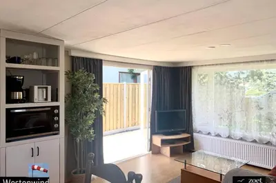 a living room with a large window and a television at Holiday-Chalet Westenwind 4p. Amsterdam & Beach in Opmeer