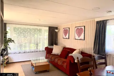 a living room with a red couch and a table at Holiday-Chalet Westenwind 4p. Amsterdam & Beach in Opmeer