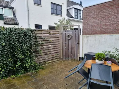 a patio with a wooden fence and a table and chairs at Tip! Noordwijk city center house in Noordwijk aan Zee