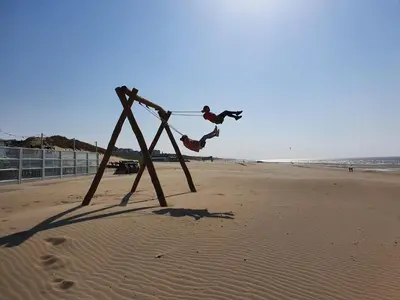 a person jumping off a swing on the beach at Tip! Noordwijk city center house in Noordwijk aan Zee