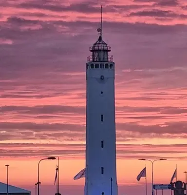 a white lighthouse with a sunset in the background at Tip! Noordwijk city center house in Noordwijk aan Zee