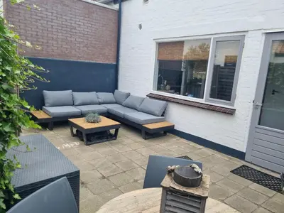 a patio with a couch and tables and a window at Tip! Noordwijk city center house in Noordwijk aan Zee