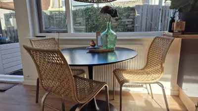 a table with chairs and a vase with a flower on it at Tip! Noordwijk city center house in Noordwijk aan Zee