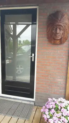 a statue of a head on the side of a building at De indiaan in Noord-Scharwoude