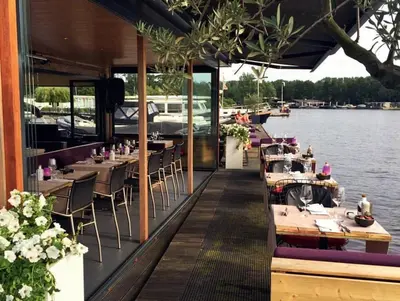 a restaurant on the water with tables and chairs at Motor Yacht Amstelle in Amsterdam
