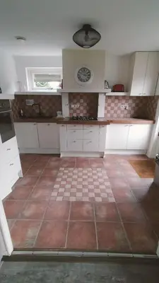 a kitchen with white cabinets and a tile floor at Vakantiehuis Horsterwold in Zeewolde