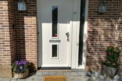 a white door on a brick house with flowers in baskets at Vakantiehuis Horsterwold in Zeewolde