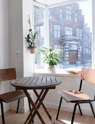 a wooden table and two chairs in front of a window at Cosy Tiny House 5 min walk Keukenhof included entrance keukenhof in Lisse