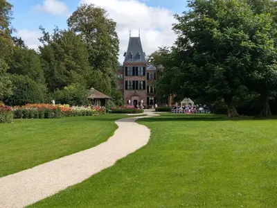a walkway through a park with a building in the background at Cosy Tiny House 5 min walk Keukenhof included entrance keukenhof in Lisse
