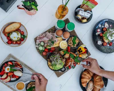a table with plates of food and people eating food at Harbour Suites Boutique Hotel in Monnickendam