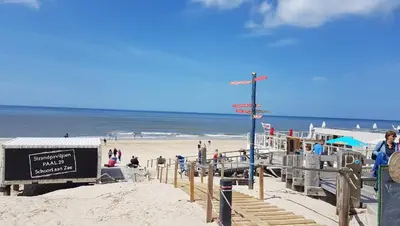 a beach with people on the sand and the ocean at Lodge 'De Groene Parel' in Schoorl