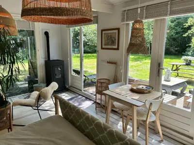 a living room with a couch and a table and chairs at Lodge 'De Groene Parel' in Schoorl