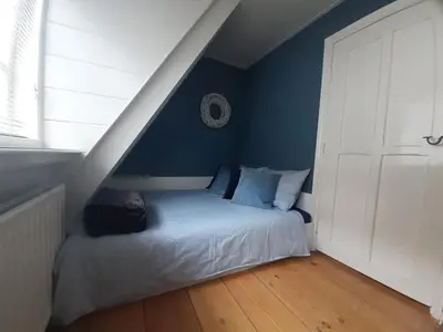 a bedroom with a bed with a blue wall at Het Schaager Waapen in Alkmaar