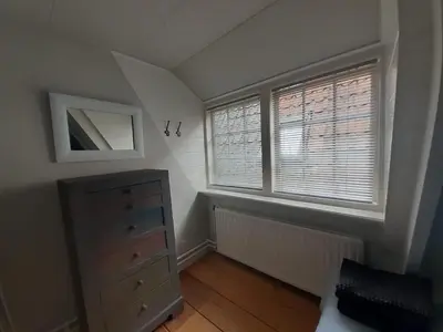 a bedroom with a dresser and two windows at Het Schaager Waapen in Alkmaar