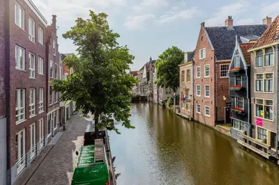 a canal in a city with buildings and a green boat at Het Schaager Waapen in Alkmaar