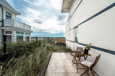 a patio with two chairs and a table on the side of a building at Keller Beach in Zandvoort