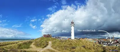 a lighthouse on top of a hill next to the ocean at Zomerhuisje achter Torenlicht in Egmond aan Zee