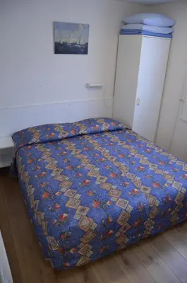 a bed with a blue comforter in a bedroom at Zomerhuisje achter Torenlicht in Egmond aan Zee