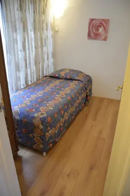 a small bed in a room with a wooden floor at Zomerhuisje achter Torenlicht in Egmond aan Zee