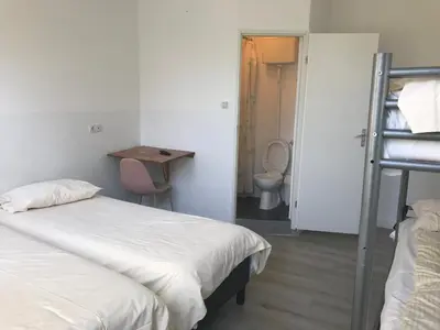 a bedroom with two beds and a bathroom with a toilet at hotel Oosterpark in Amsterdam