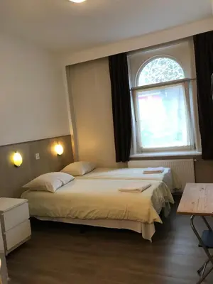 two beds in a room with a window at hotel Oosterpark in Amsterdam
