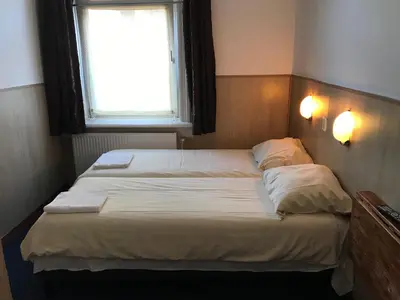 two beds in a small room with a window at hotel Oosterpark in Amsterdam